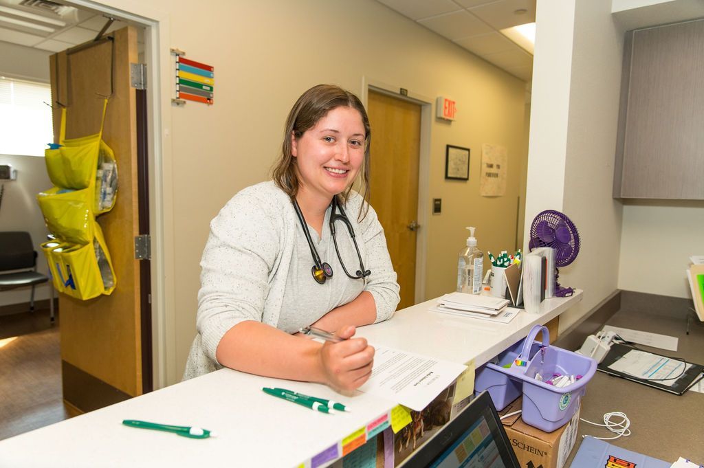 A woman with a lab coat and stethescope around her neck holding a pen.