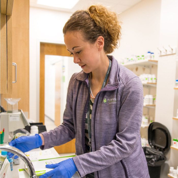 A woman wearing blue gloves is working in a pharmacy.