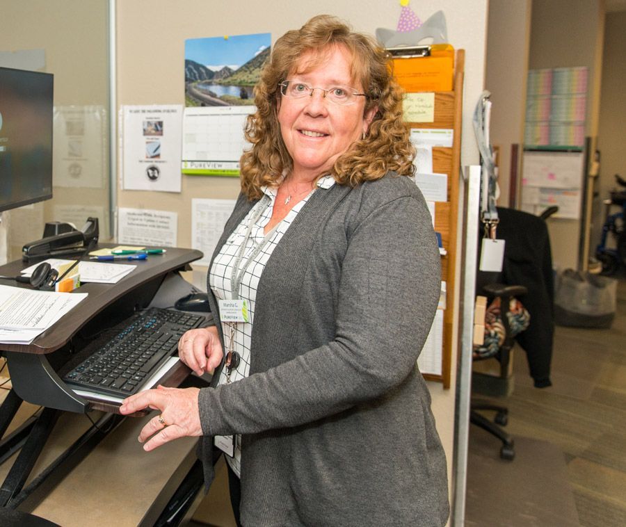 A woman is standing in front of a desk with a keyboard.