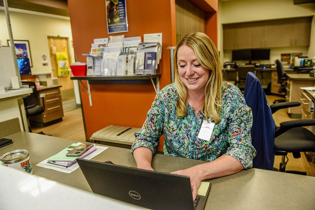 A woman is sitting at a desk in front of a dell computer.