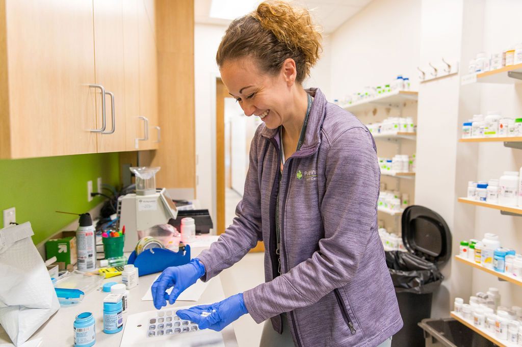 A woman wearing blue gloves is working in a pharmacy.