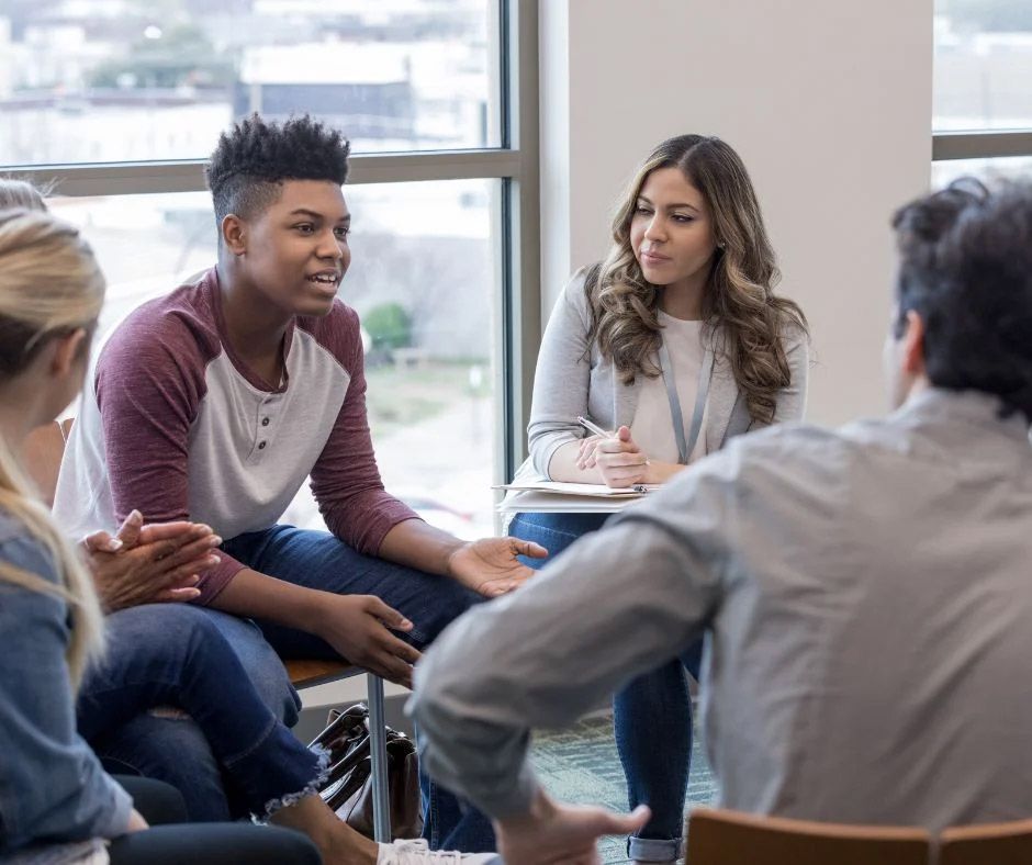 A group of people are sitting in a circle talking to each other.