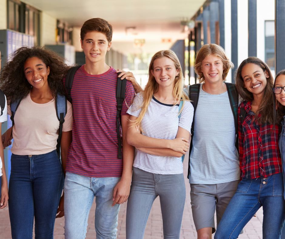 A group of young people are standing next to each other in a hallway.