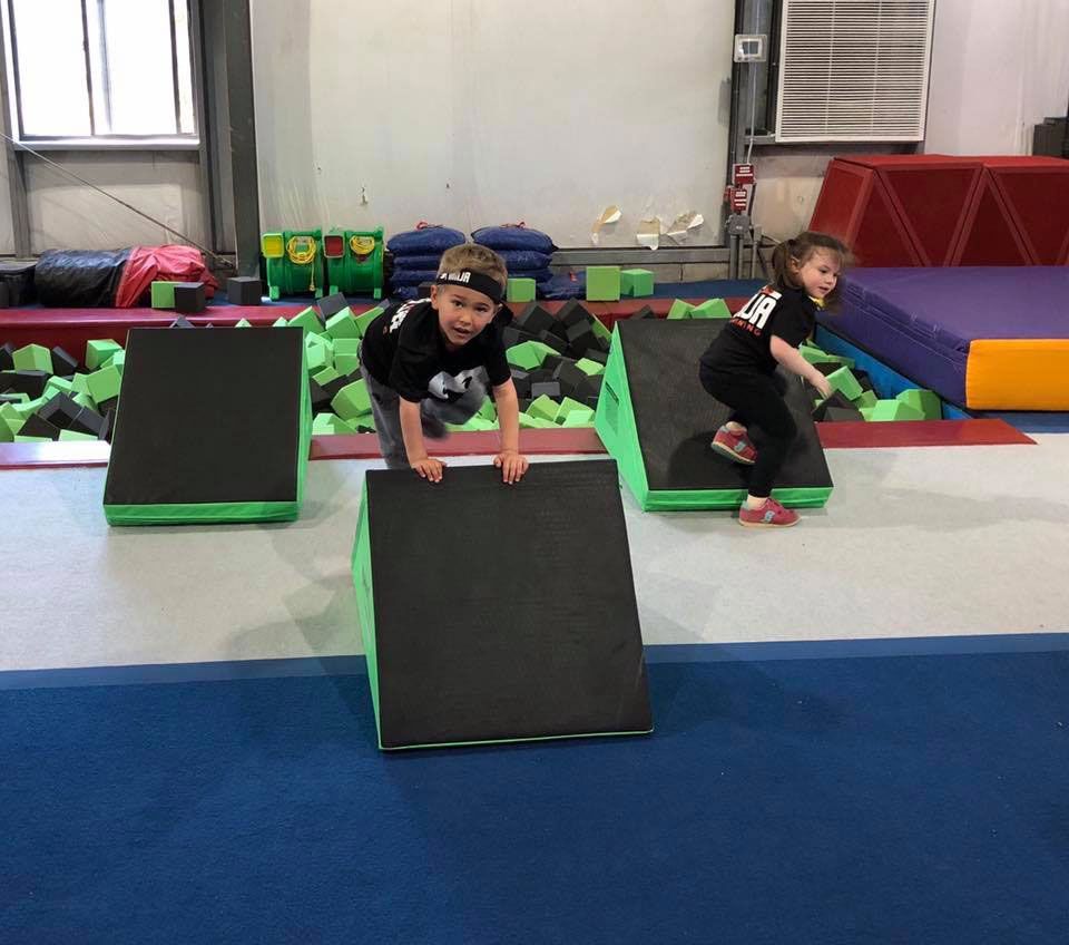 Kids climbing over soft foam obstacles during a Ninja class