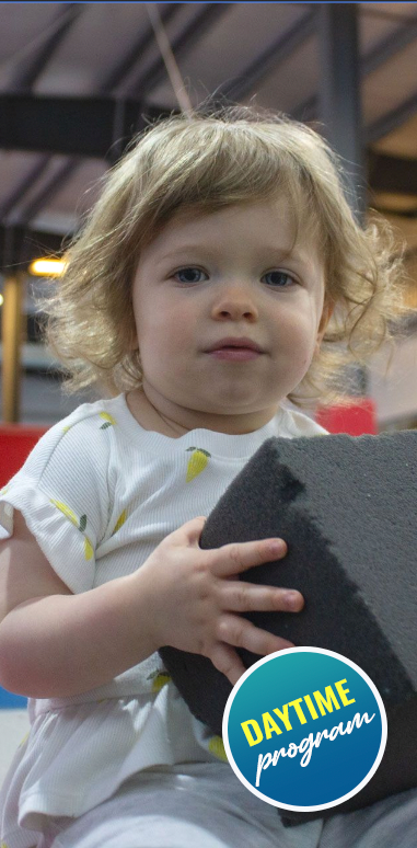 Toddler playing with a soft foam block in the Daytime Program at Paramount Gymnastics