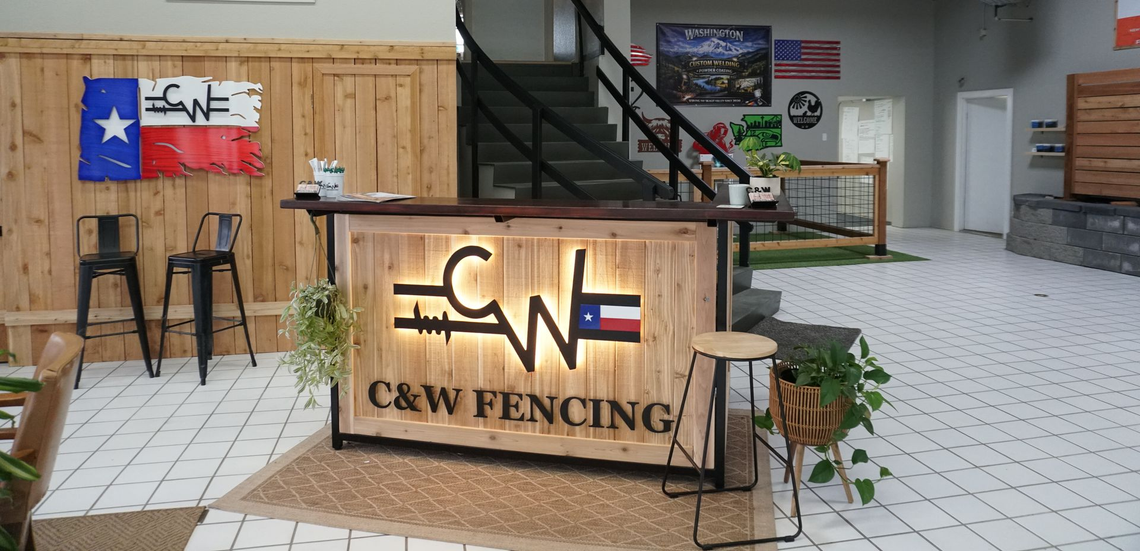 C&W Fencing booth with lit wooden counter, American flag decor, and tools on display in an indoor hall