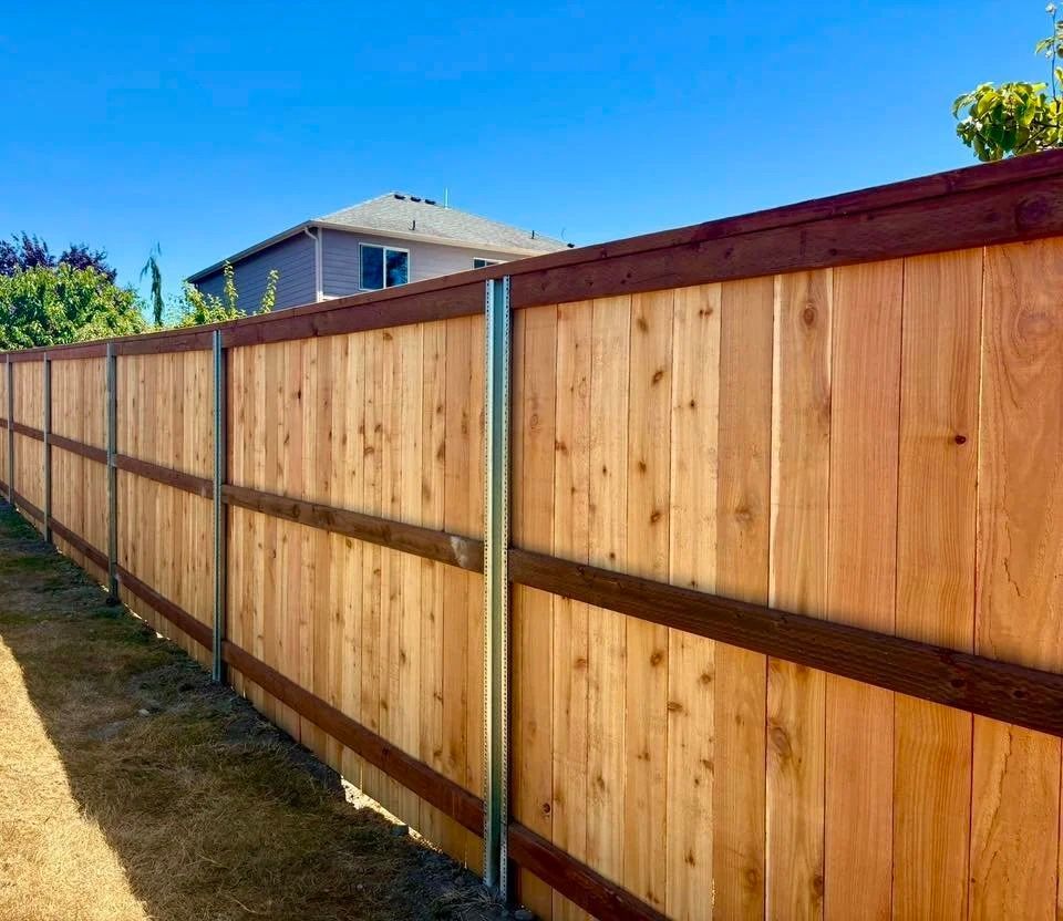 New wooden privacy fence with horizontal support rails along a backyard boundary