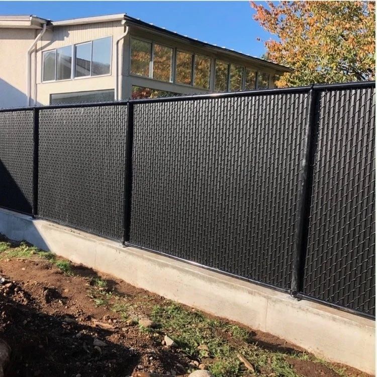 Black metal fence beside a concrete wall in front of a building on a sunny day