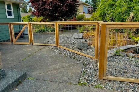 Wooden gate along a gravel driveway beside a landscaped yard and house