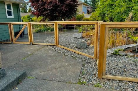 Wooden gate along a gravel driveway beside a landscaped yard and house