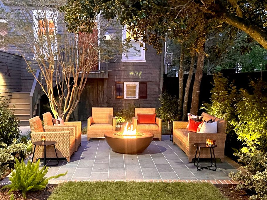 Cozy backyard patio with wicker seating, fire pit, and string lights at dusk