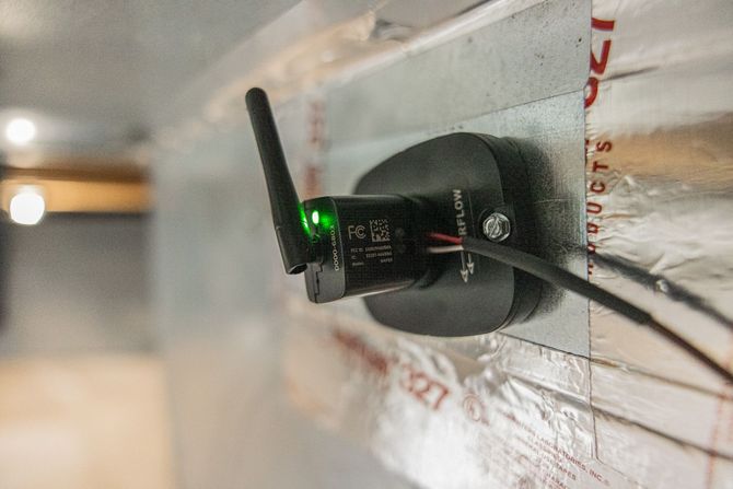 Wireless sensor mounted on a metal surface, with a green indicator light and antenna.