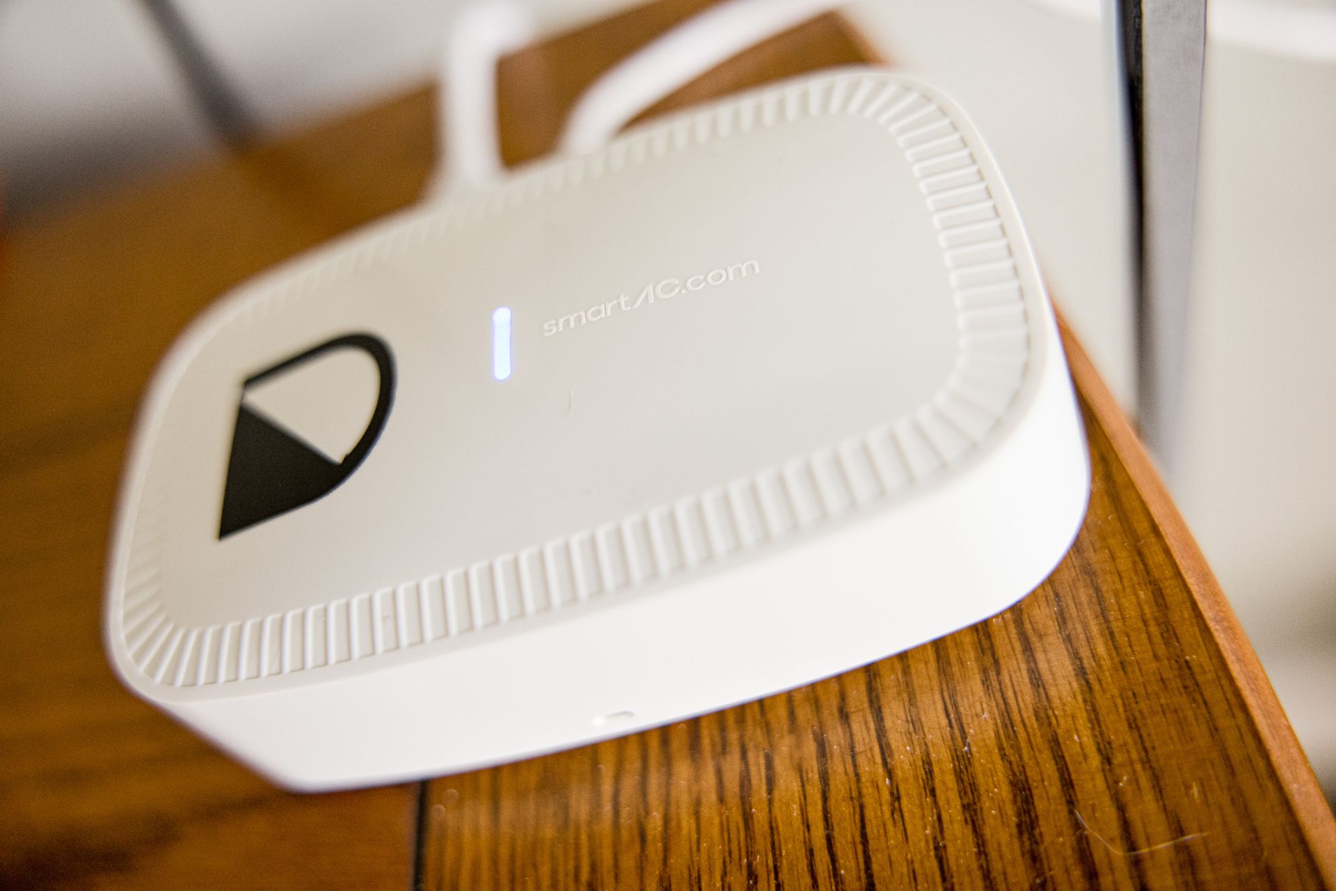 White streaming device with black logo resting on a wooden surface, close-up view