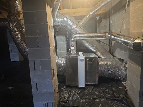 Basement with exposed HVAC ducts, insulated pipes, and utility equipment along cinder block walls.