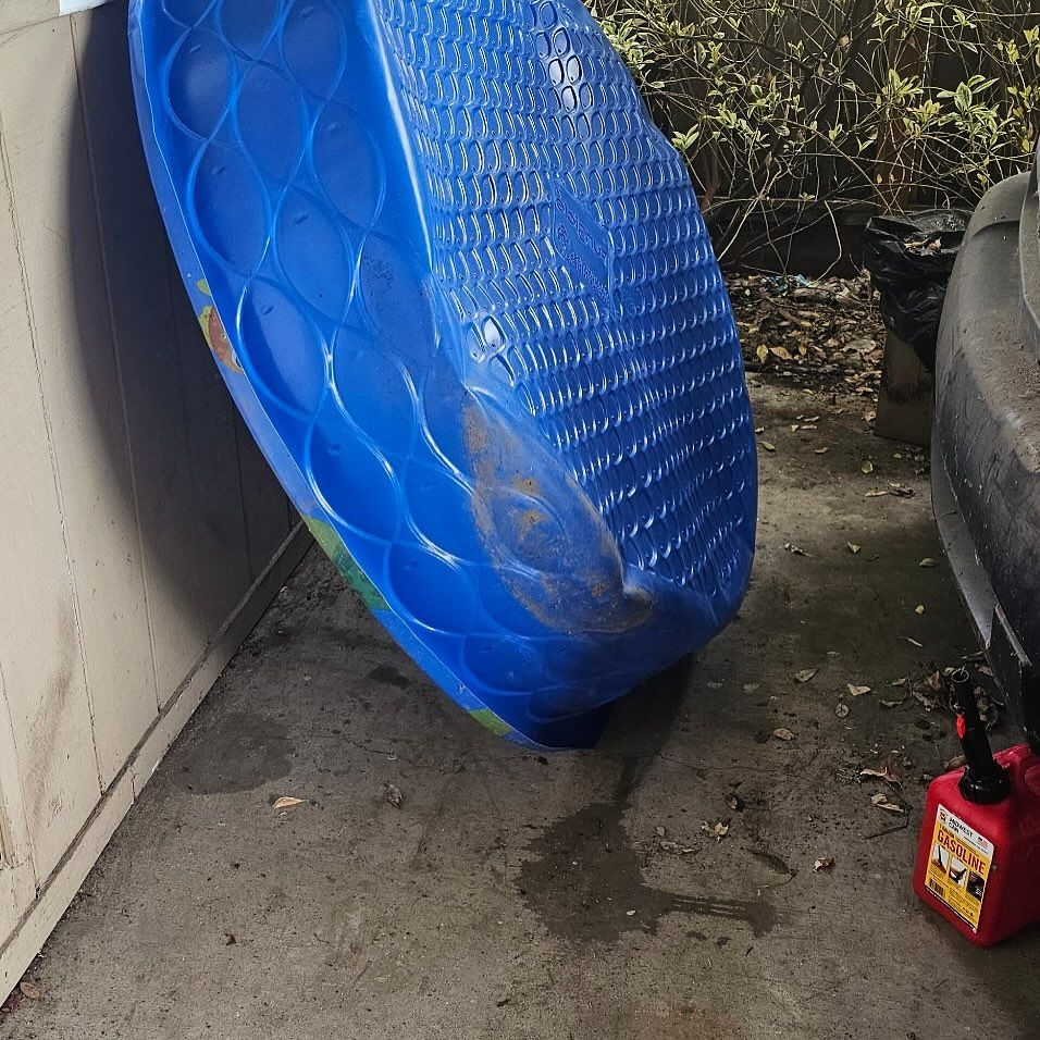 A blue plastic swimming pool is leaning against a wall