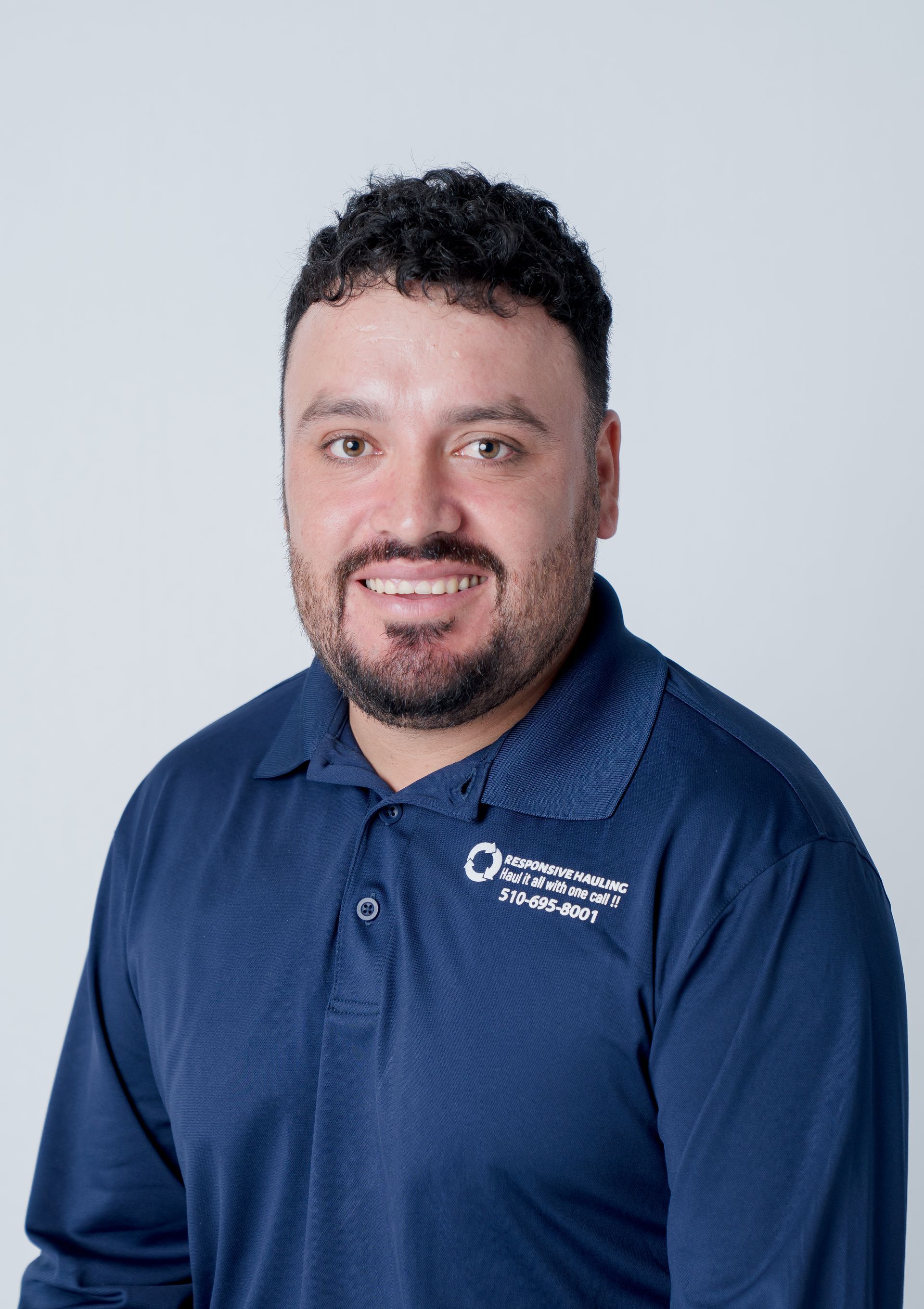 Smiling man in a navy polo with a company logo on the left chest