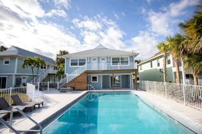 Beach house pool with lounge chairs and blue sky