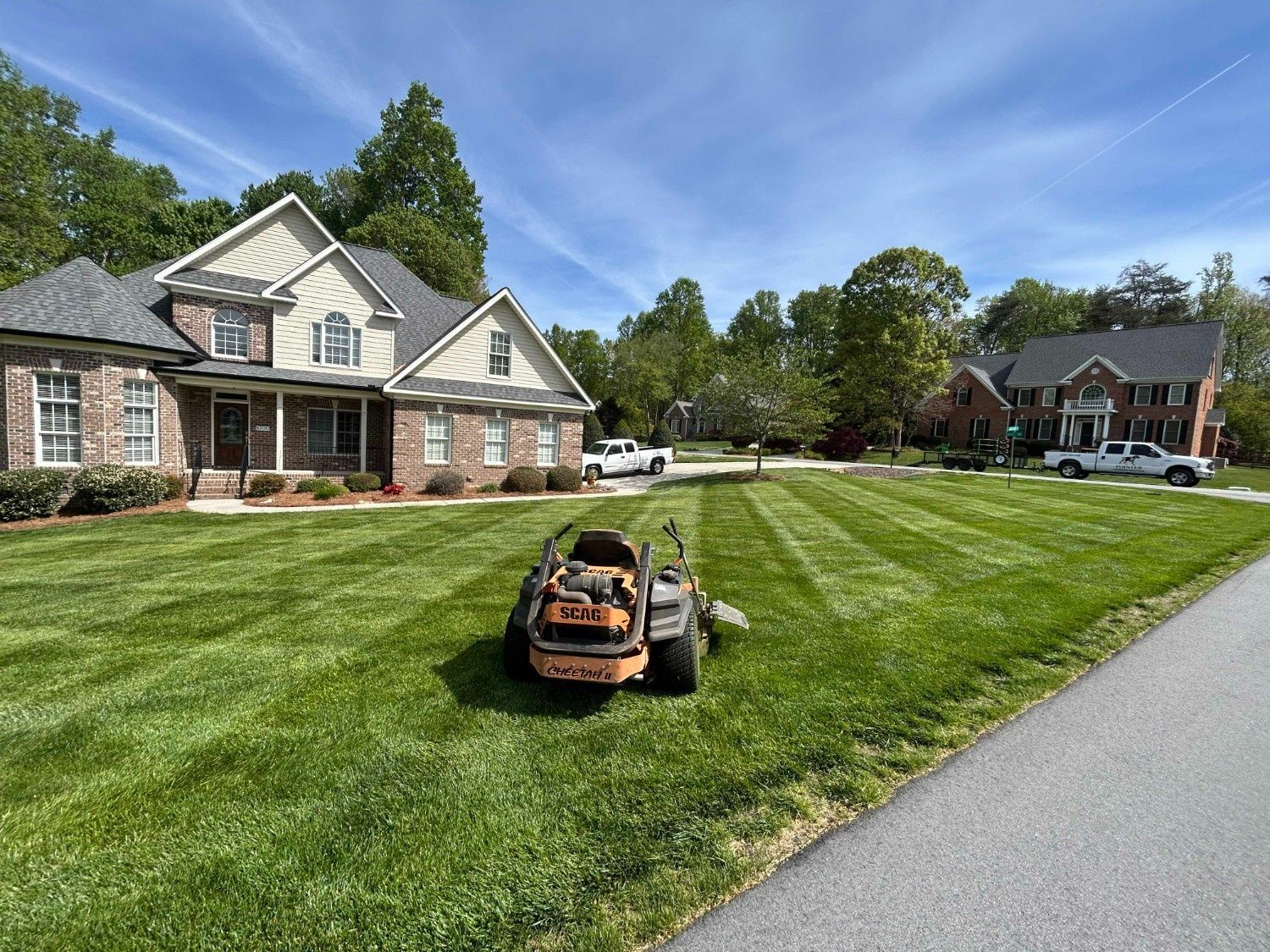 Suburban home with a wide green lawn and a lawn mower in the foreground
