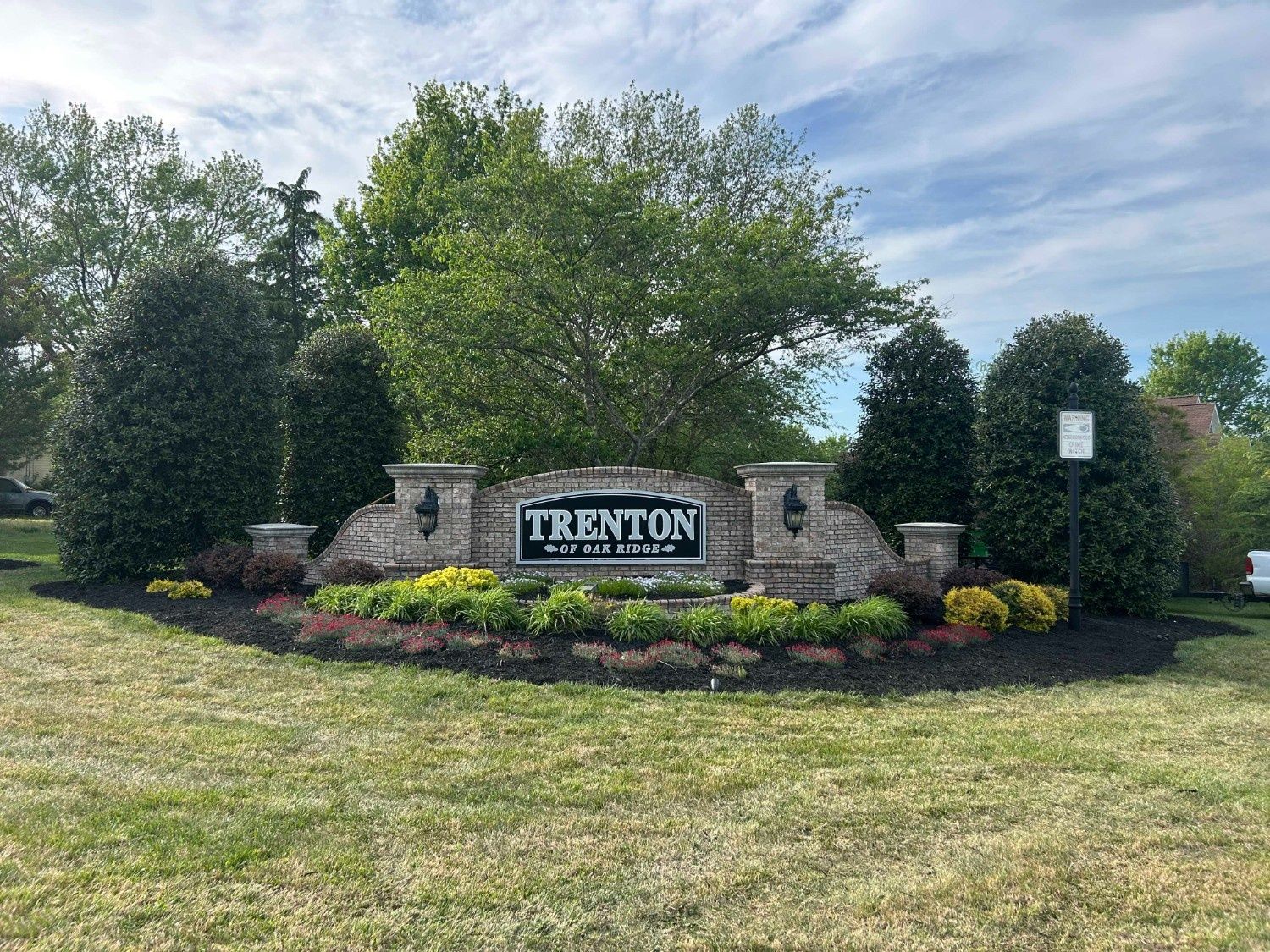 Trenton city entrance sign in a landscaped brick and stone garden with trees and flowers
