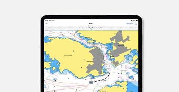 A tablet displays a marine navigation chart showing a coastal area with land, water depths, and a plotted path.