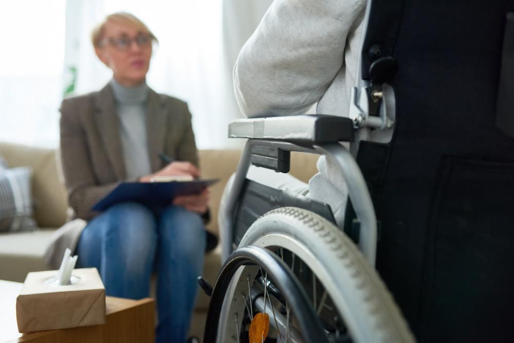 A Woman is Sitting on a Couch Next to a Man in a Wheelchair — Tony Love Lawyers in Lismore, NSW