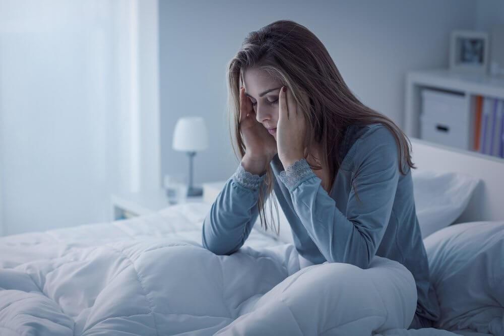 A Woman is Sitting on a Bed With Her Head in Her Hands — Tony Love Lawyers in Lismore, NSW