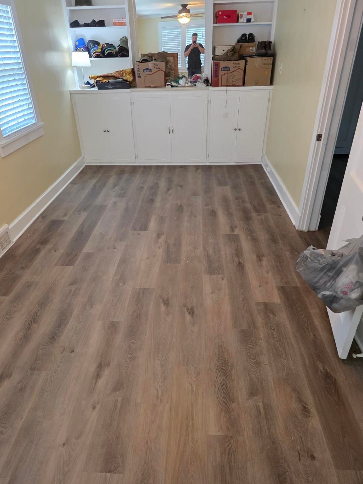 Empty room with wood flooring, white cabinets, and a mirrored wall.