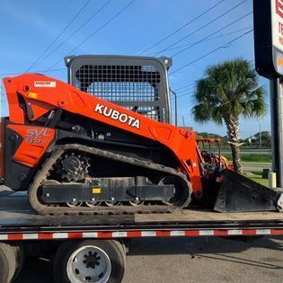 A kubota skid steer is sitting on top of a flatbed trailer.