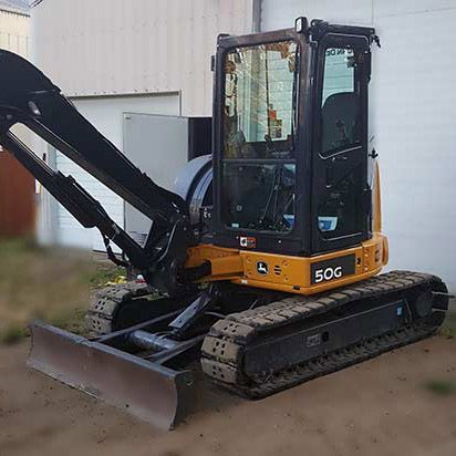 A yellow and black excavator is parked in front of a garage.