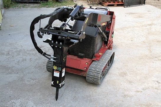 A red tractor with a hydraulic hammer attached to it