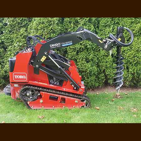 A red tractor with a drill attached to it is sitting on top of a lush green lawn.