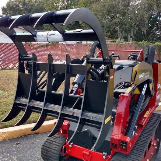 A red and black tractor with a large claw attached to it