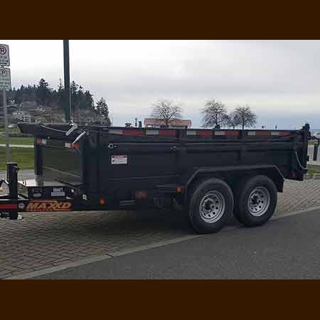 A dump trailer is parked on the side of the road.