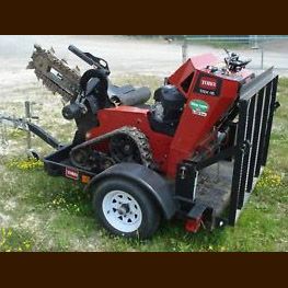 A red tractor is parked on a trailer in the grass.