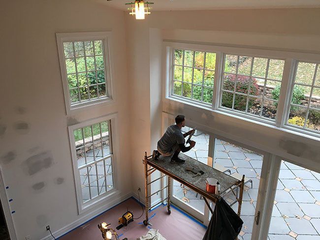 painter of scaffolding working on painting interior
