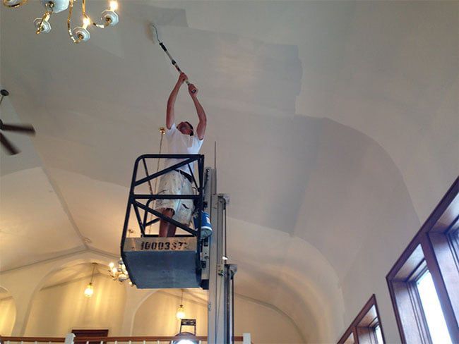 painter on a lift painting the ceiling