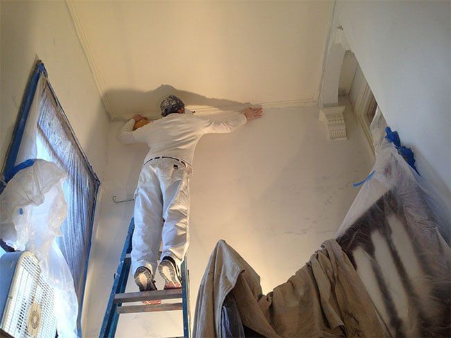 professional painter reinstalling crown molding for painting