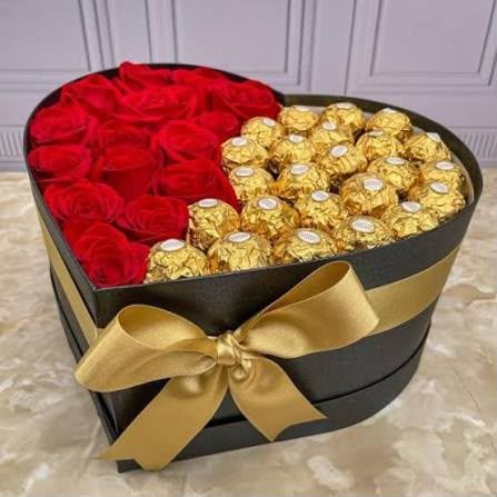 Caja con forma de corazón de rosas rojas y bombones Ferrero Rocher dorados, con un lazo dorado