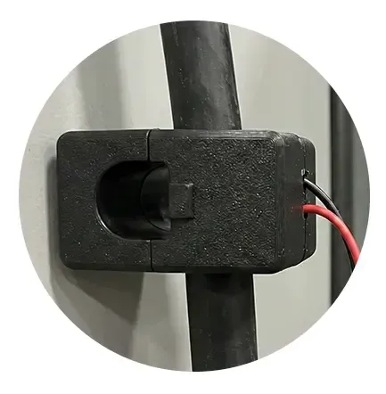 A black, rectangular split-core current transformer sensor clamped around a black electrical cable.