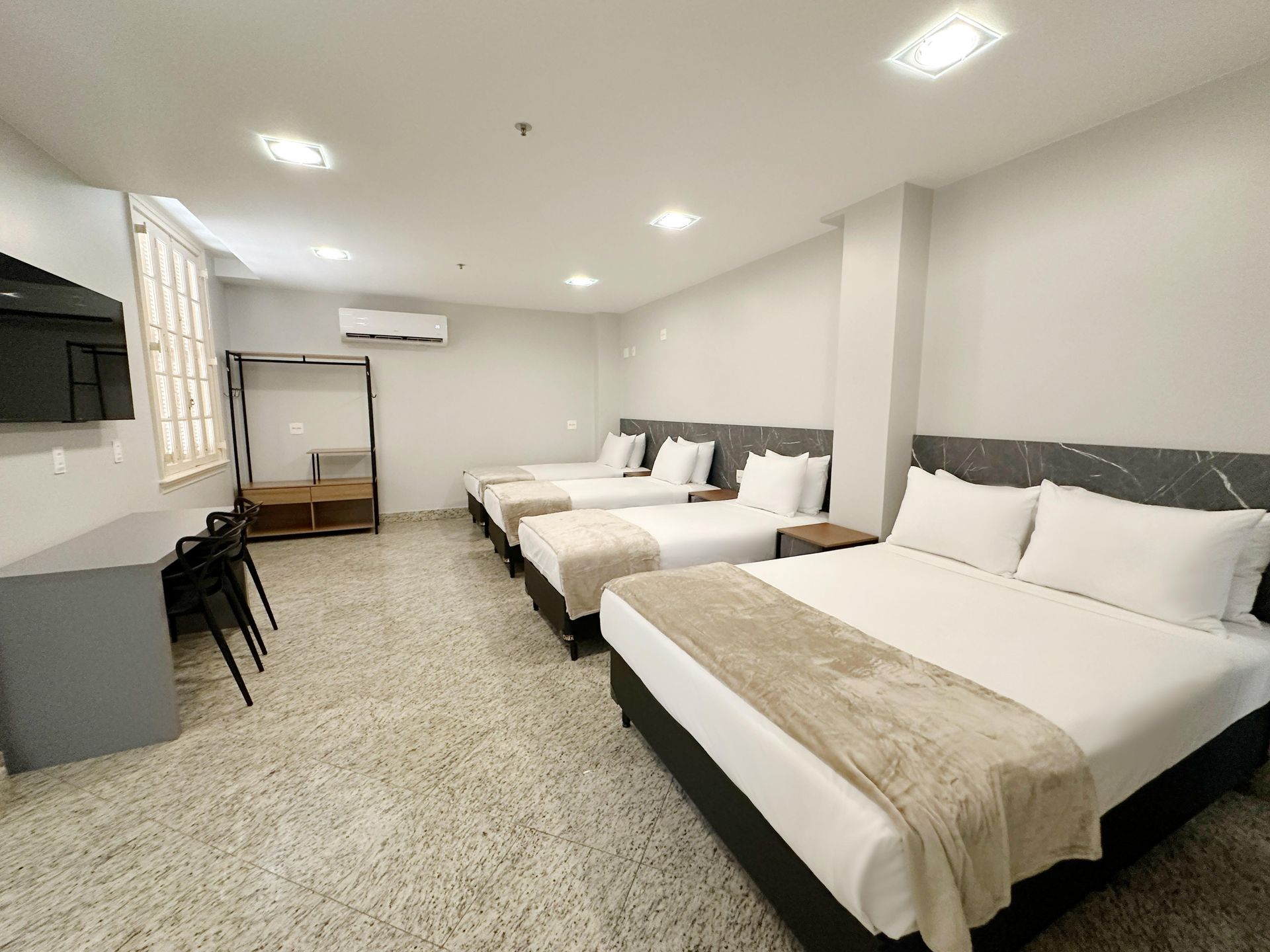 Um quarto de hotel com quatro camas e uma escrivaninha.