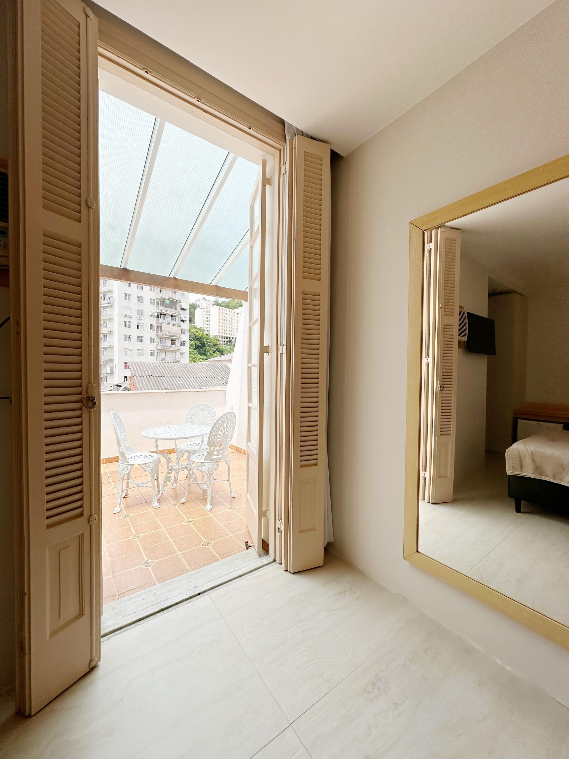 Um quarto com um espelho grande e uma varanda