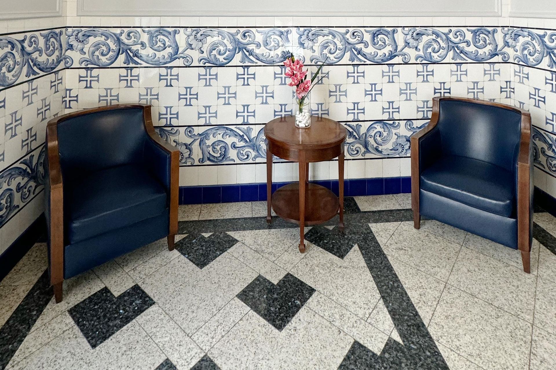 Duas cadeiras e uma mesa em uma sala com azulejos azuis e brancos