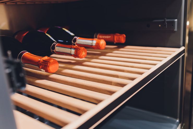 Orange-handled screwdrivers resting on wooden shelves inside a dark cabinet Orange-handled screwdrivers resting on wooden shelves inside a dark cabinet