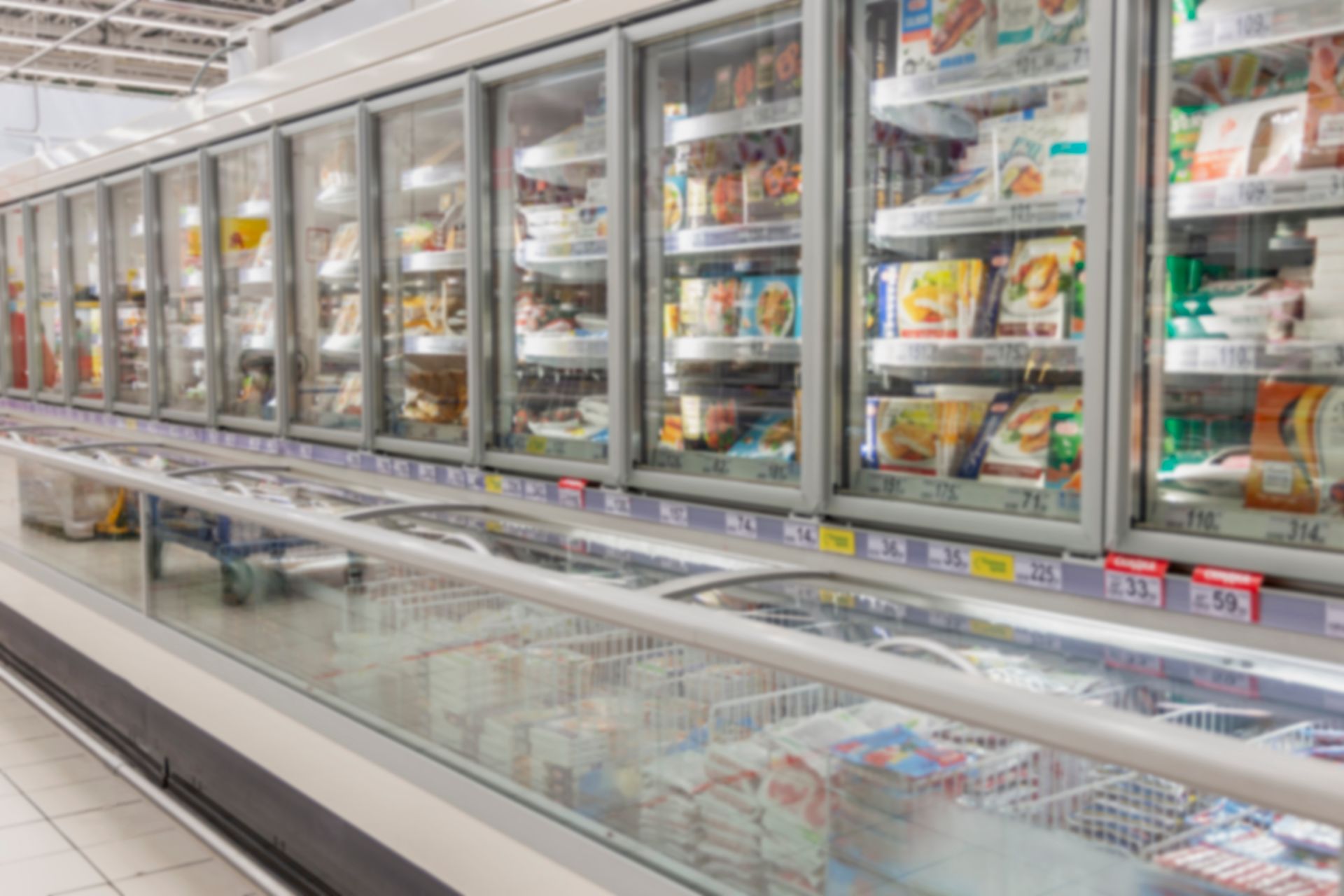 Frozen food aisle with glass-door freezers stocked with packaged meals and desserts Frozen food aisle with glass-door freezers stocked with packaged meals and desserts