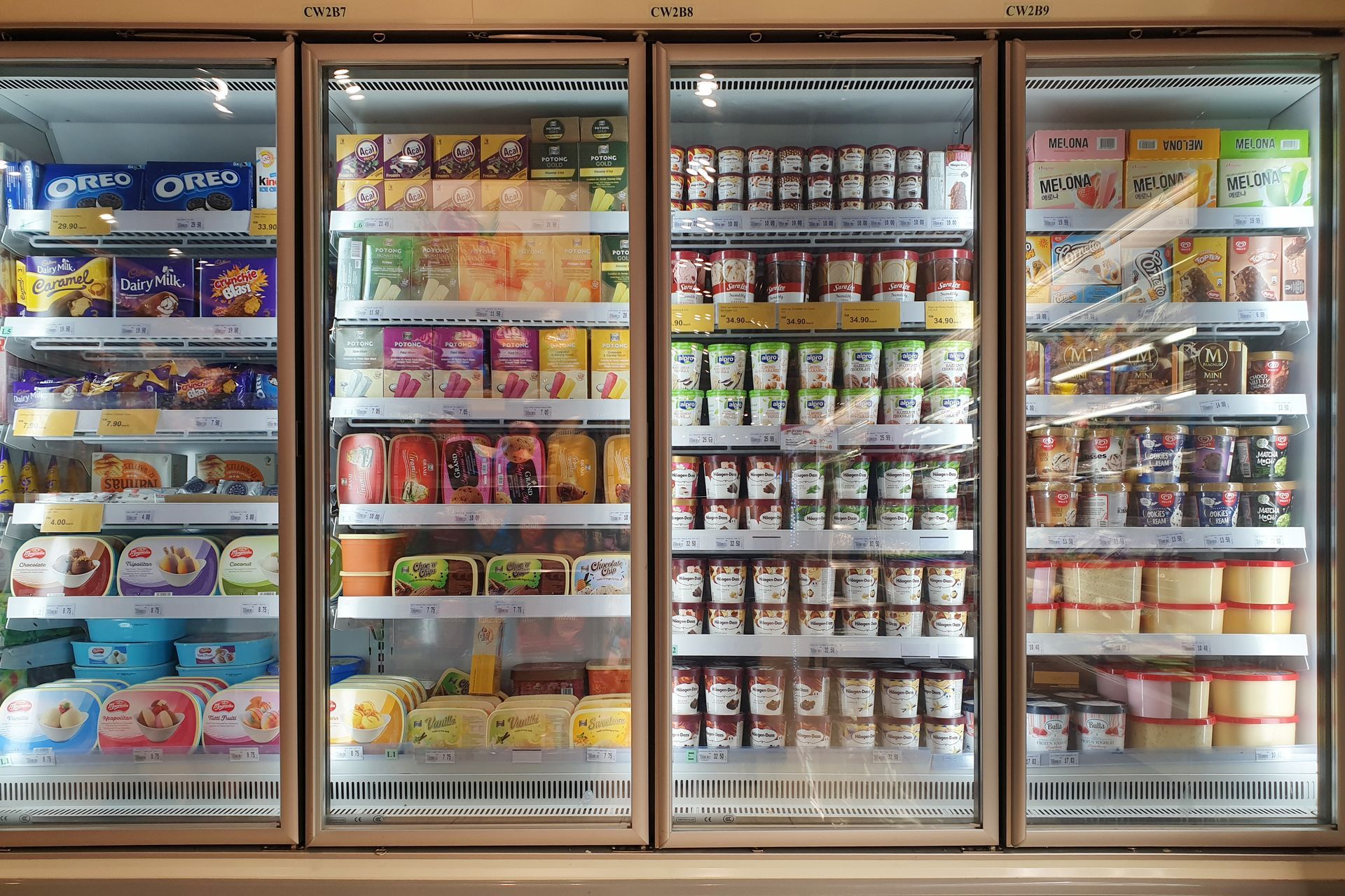 Refrigerated grocery display with assorted packaged snacks, drinks, and dairy products behind glass doors Refrigerated grocery display with assorted packaged snacks, drinks, and dairy products behind glass doors