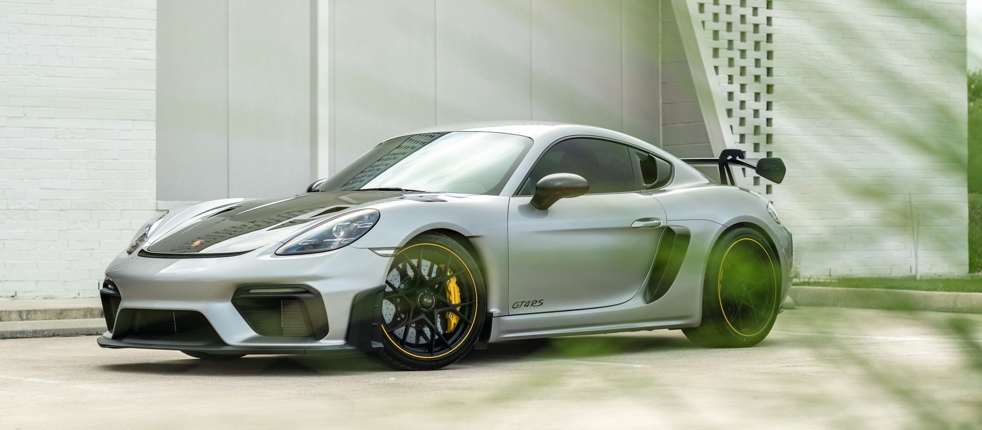 A silver porsche 911 gt4 rs is parked in front of a building.