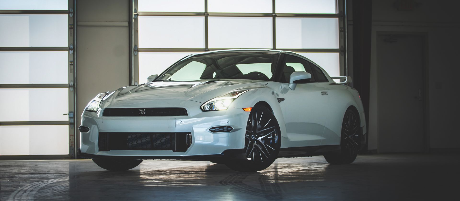 A white sports car is parked in a garage.