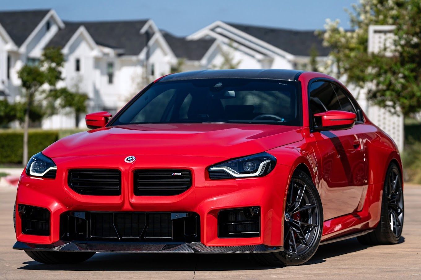 A red bmw m6 is parked in front of a white house.