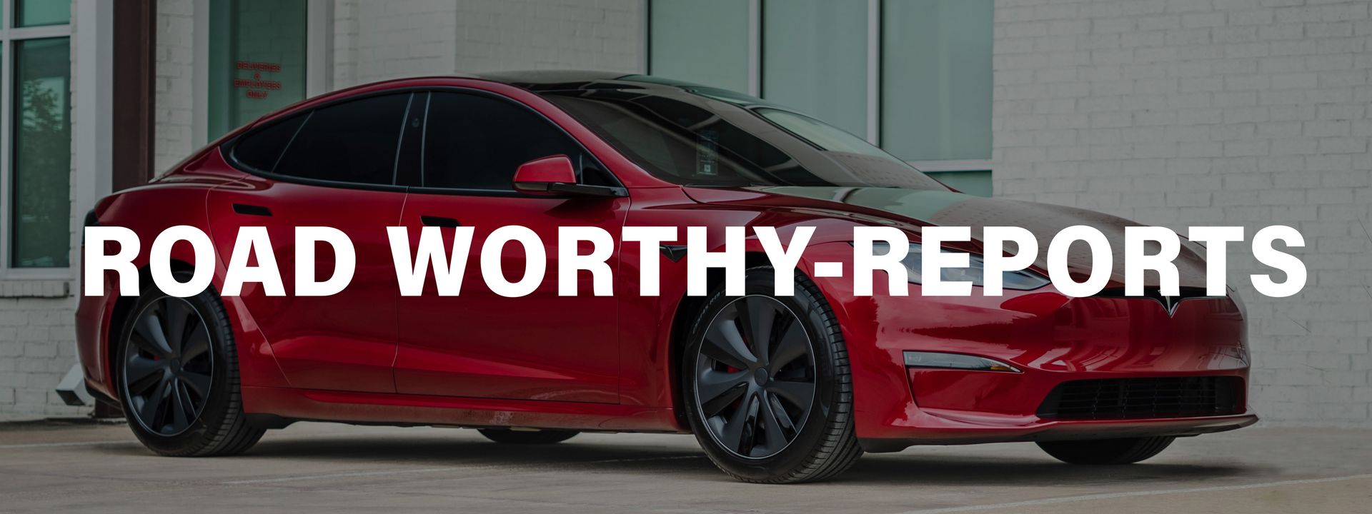 A red tesla model s is parked in front of a building.