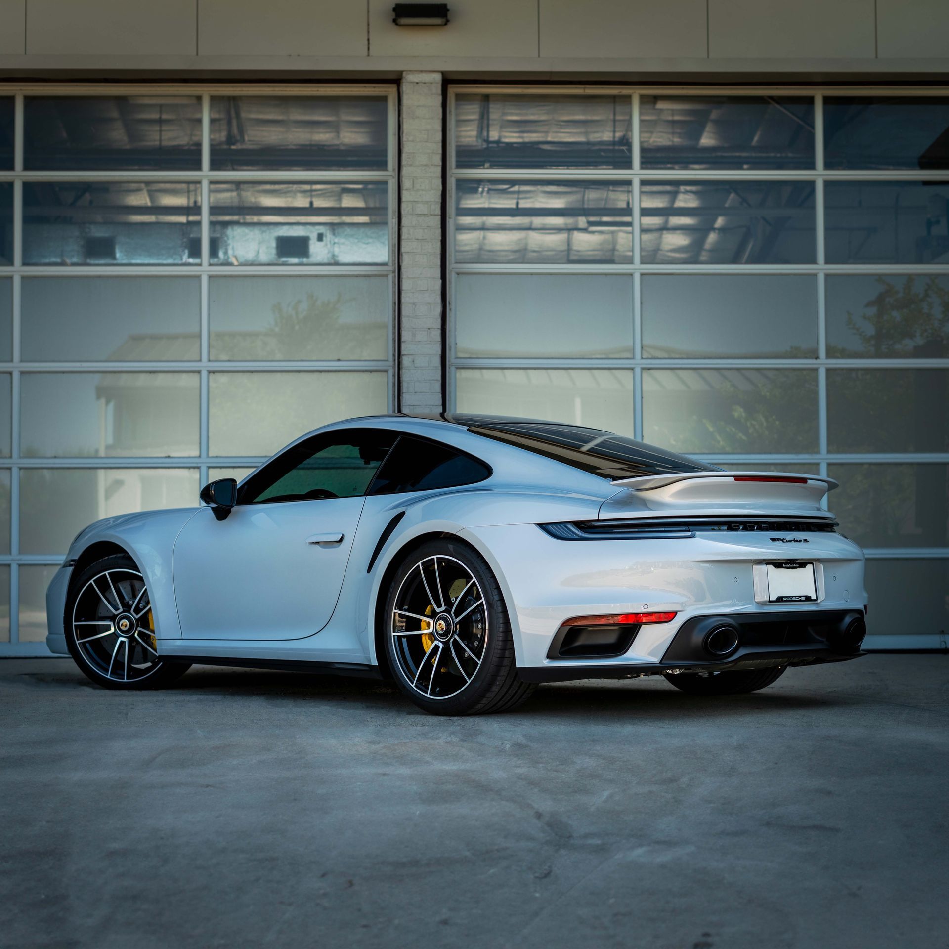 A white sports car is parked in front of a garage door.